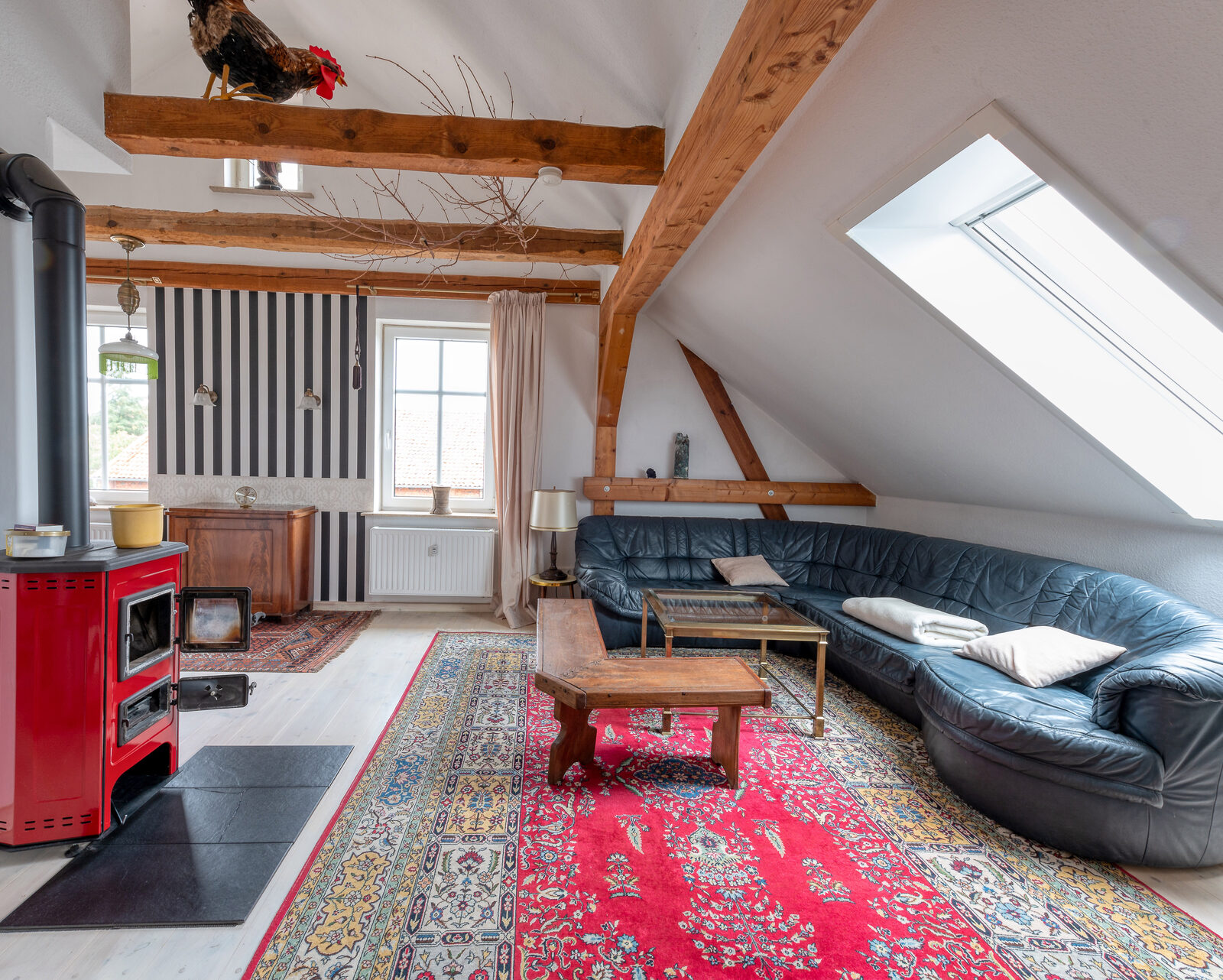Adlerwohnung — Wohnzimmer mit Kaminofen und sichtbaren Dachbalken